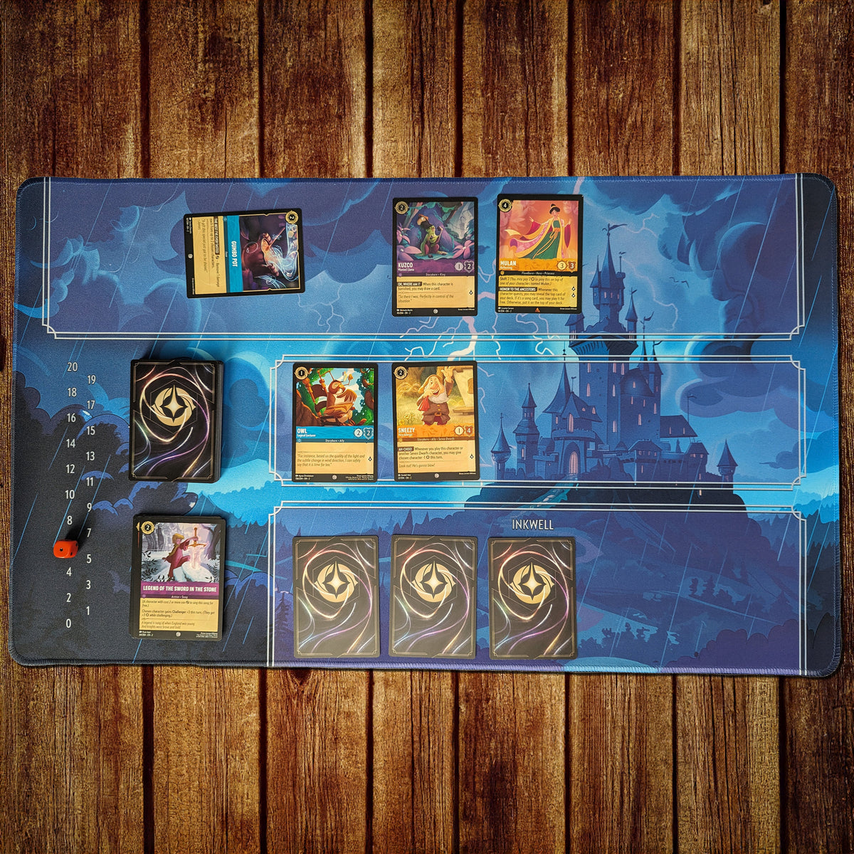 Disney Lorcana 24" x 14" playmat made of 3 mm neoprene with stitched edges and non-slip rubber backing. Features zones for Lore tracking, deck and discard piles, Inkwell management, and play area. Optional zone-free design available for a clean, customizable layout.