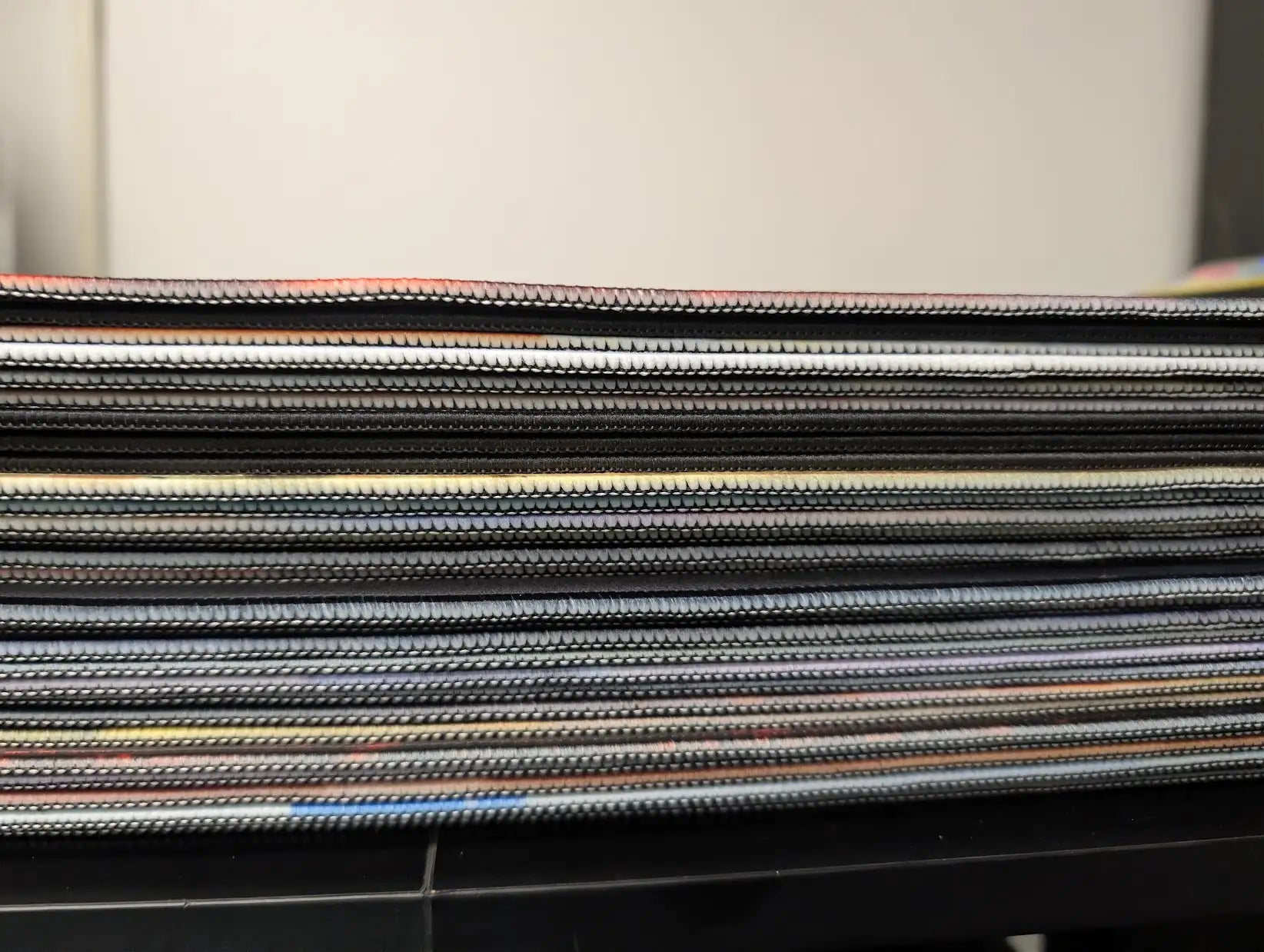 Stack of black and gray textured fabric samples with subtle color accents.